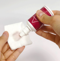 Hand holding a small bottle with a white cap against a white background